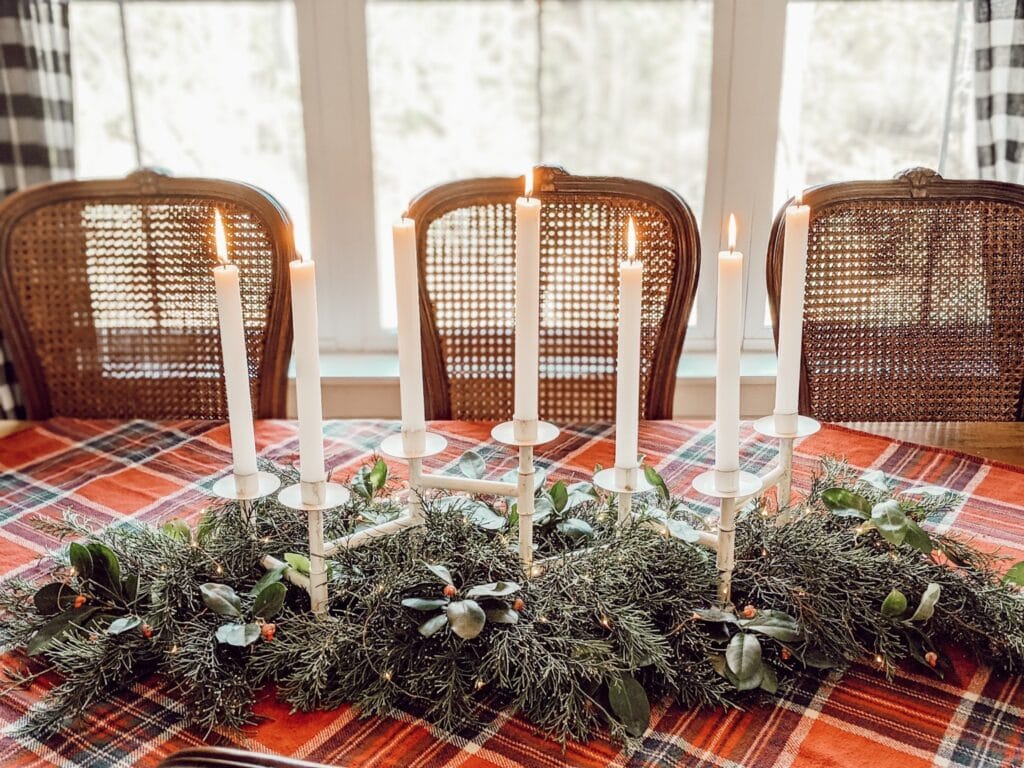 christmas tablescape with red plaid tablecloth, candles, and fresh greenery